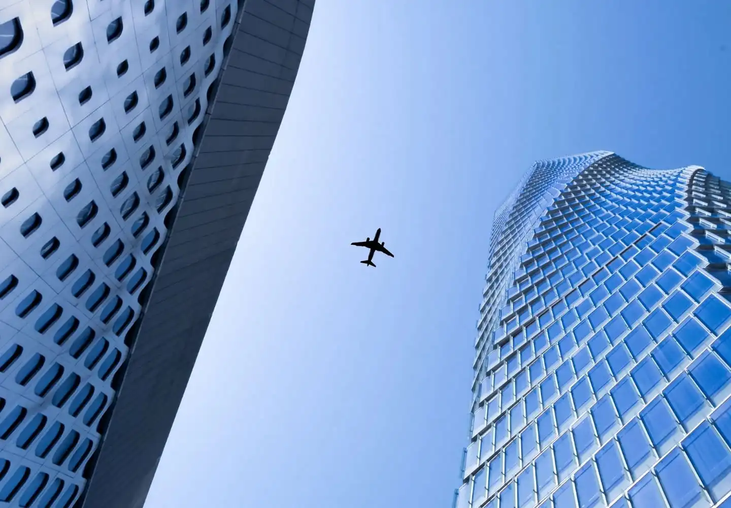 Commercial aircraft aircraft flying between modern buildings, representing the international aerospace industry