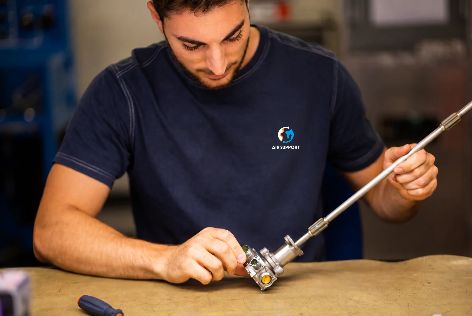 Air Support technician inspecting an aircraft component at a workshop bench